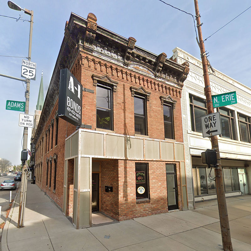 Historic brick building with a prominent sign for A-1 Bonds, located at a street corner marked by directional signs.